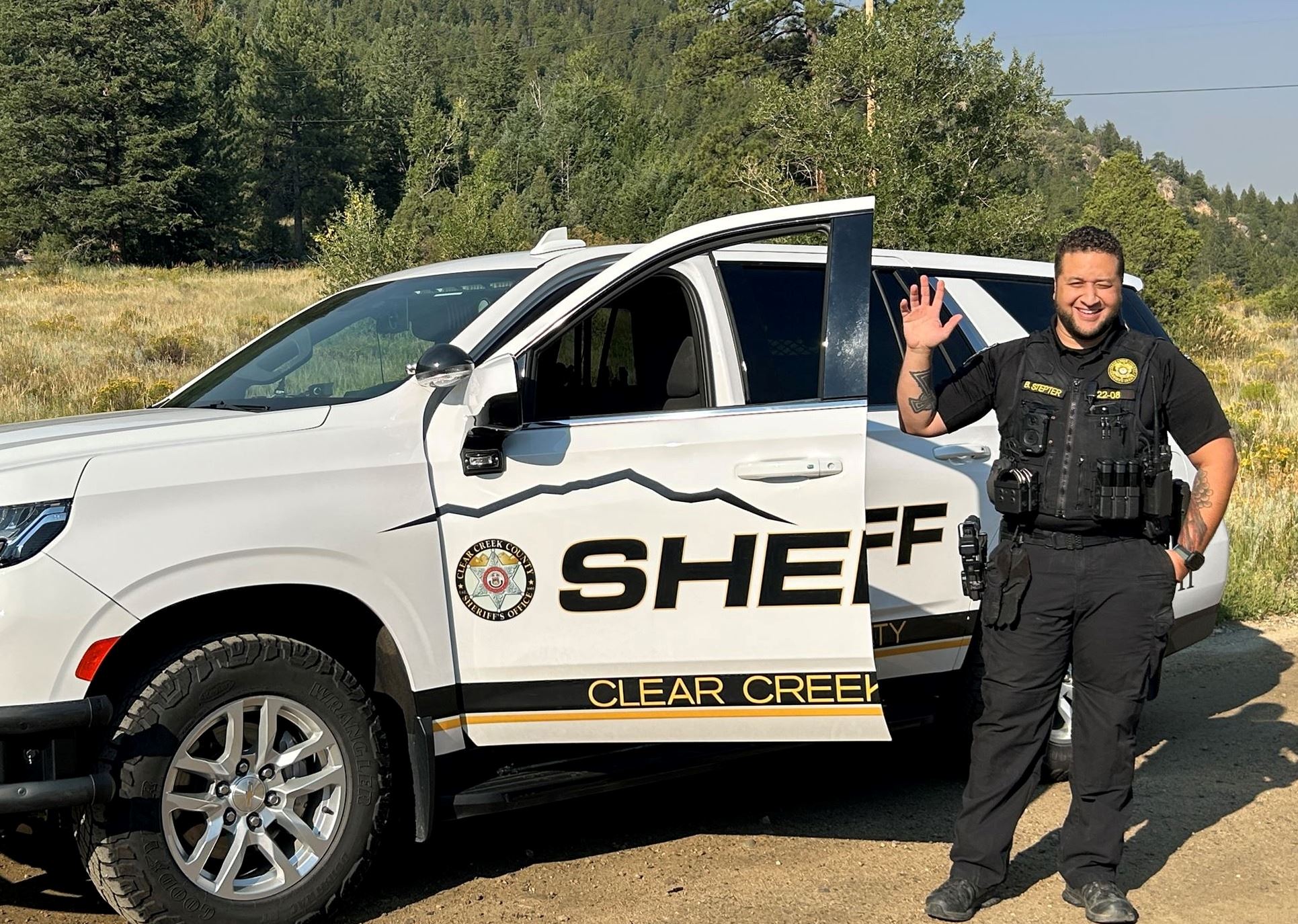Deputy waves beside his patrol vehicle