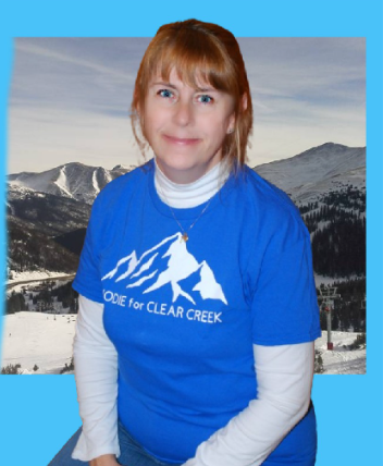 Commissioner Hartman-Ball poses in a blue shirt for a photo.